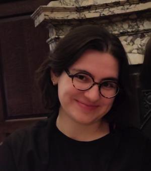 Woman with short brown hair in front of a green bush